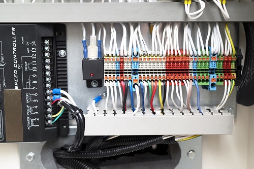Electrical panel with multi-colored wires showing a voltage distributor with circuit breakers. 